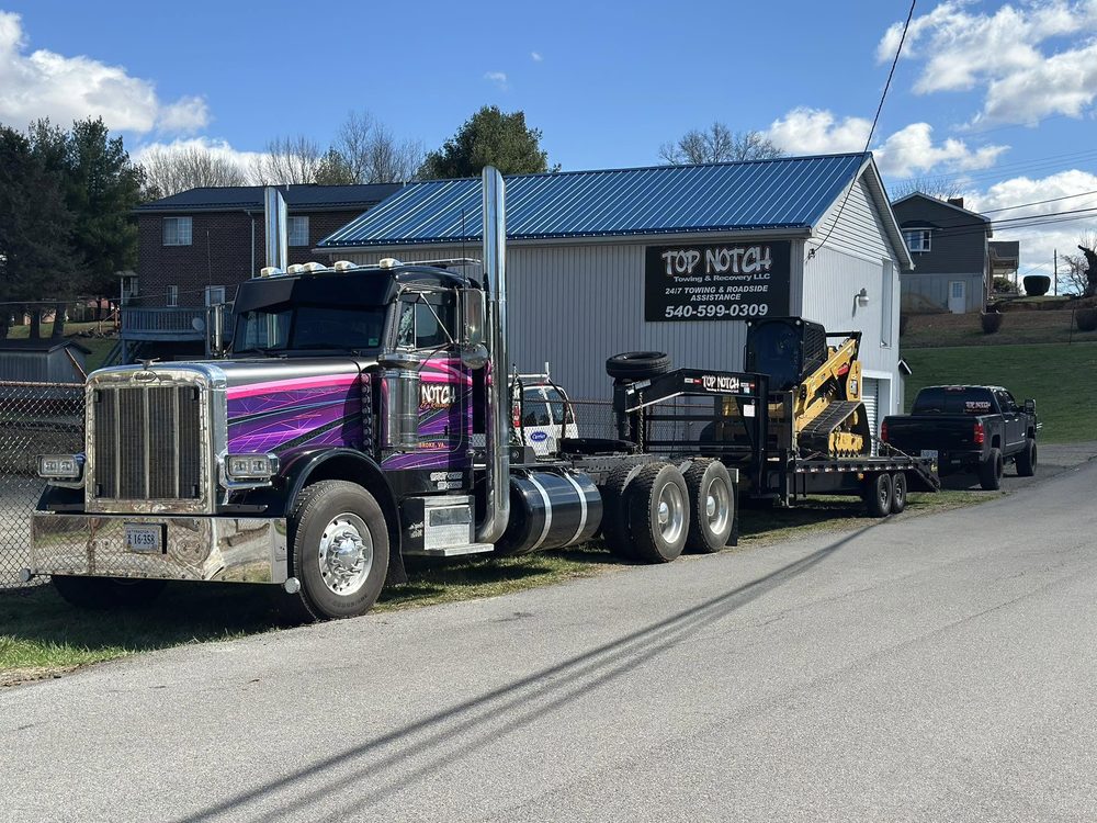 Top Notch's custom purple Peterbilt with a gooseneck trailer hauling a Cat skid steer, parked at the shop