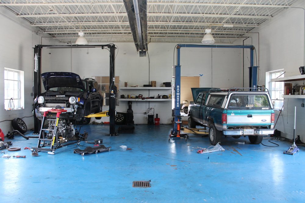 Two vehicles raised on the two-post lifts inside the Top Notch repair bay